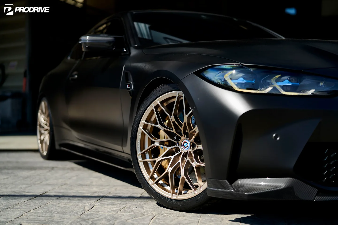 Bronskleurige velg onder een matzwarte BMW M4