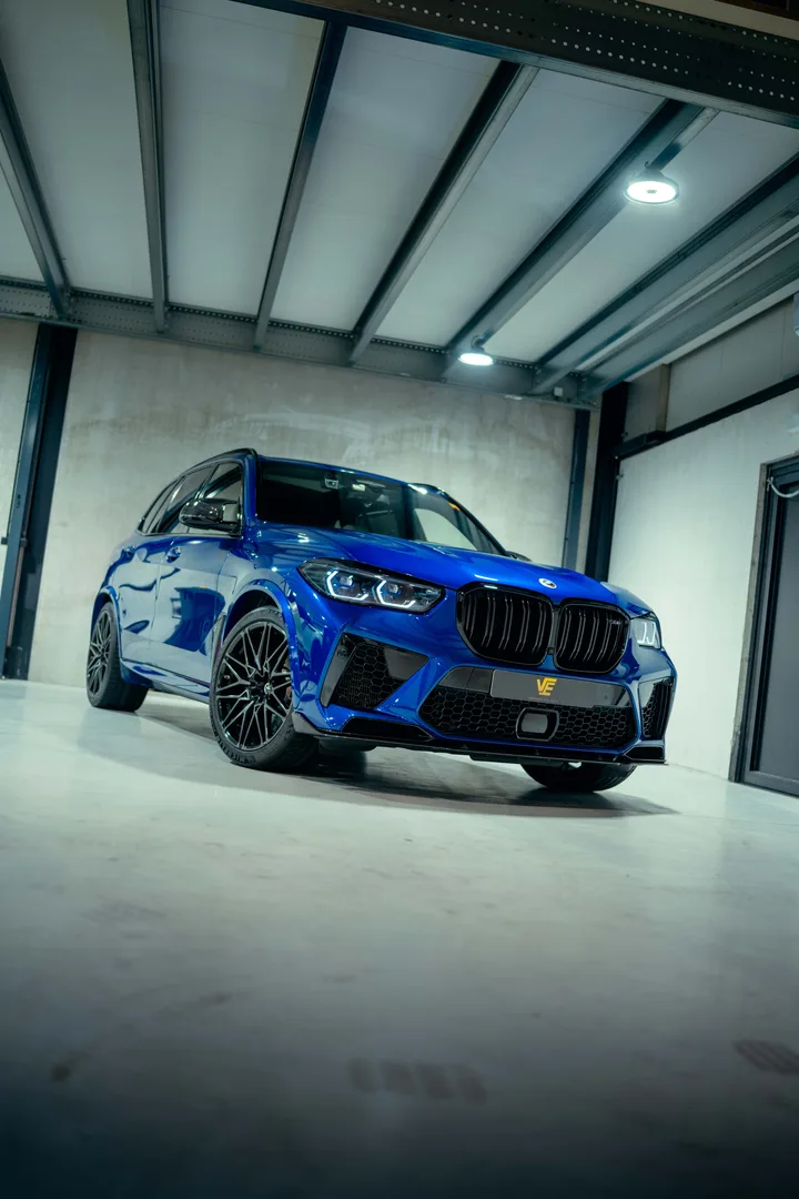 Blauwe BMW X5M Competition in de studio, schuin van voren