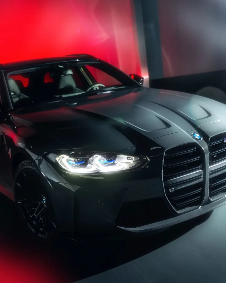 Grijze BMW M3 Touring schuin van voren voor rood licht