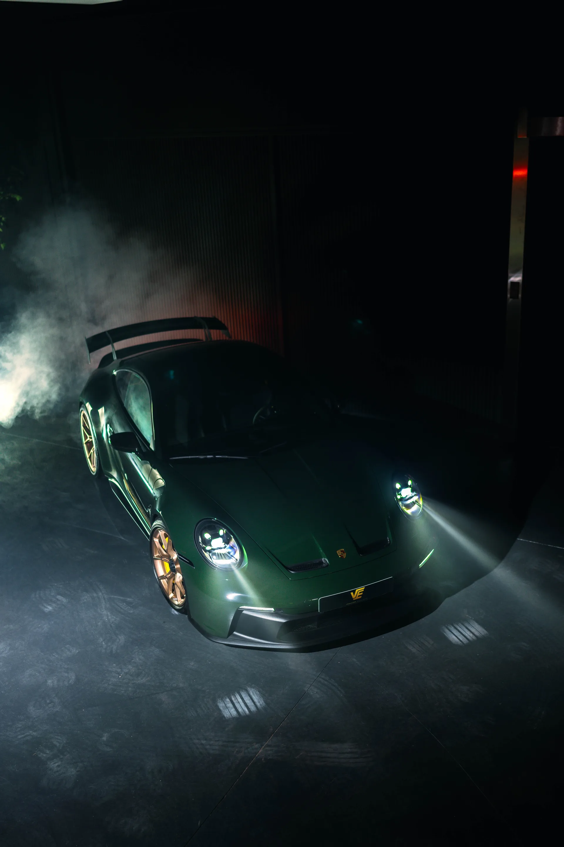 Groene Porsche 992 GT3 met gouden velgen en de kentekenplaat van Verhagen Exclusive, van bovenaf gezien in een donkere studio