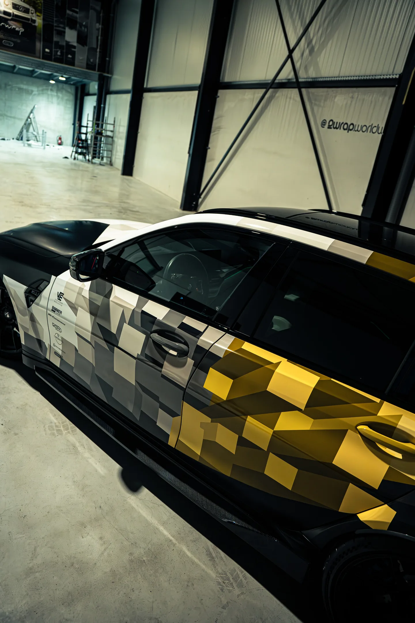 BMW M3 Touring met een custom design wrap in wit, grijs en goud, van opzij gezien