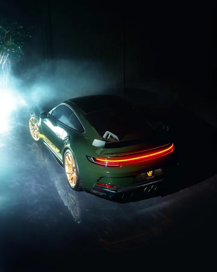 Groene Porsche 992 GT3 schuin van achteren in rook en tegenlicht
