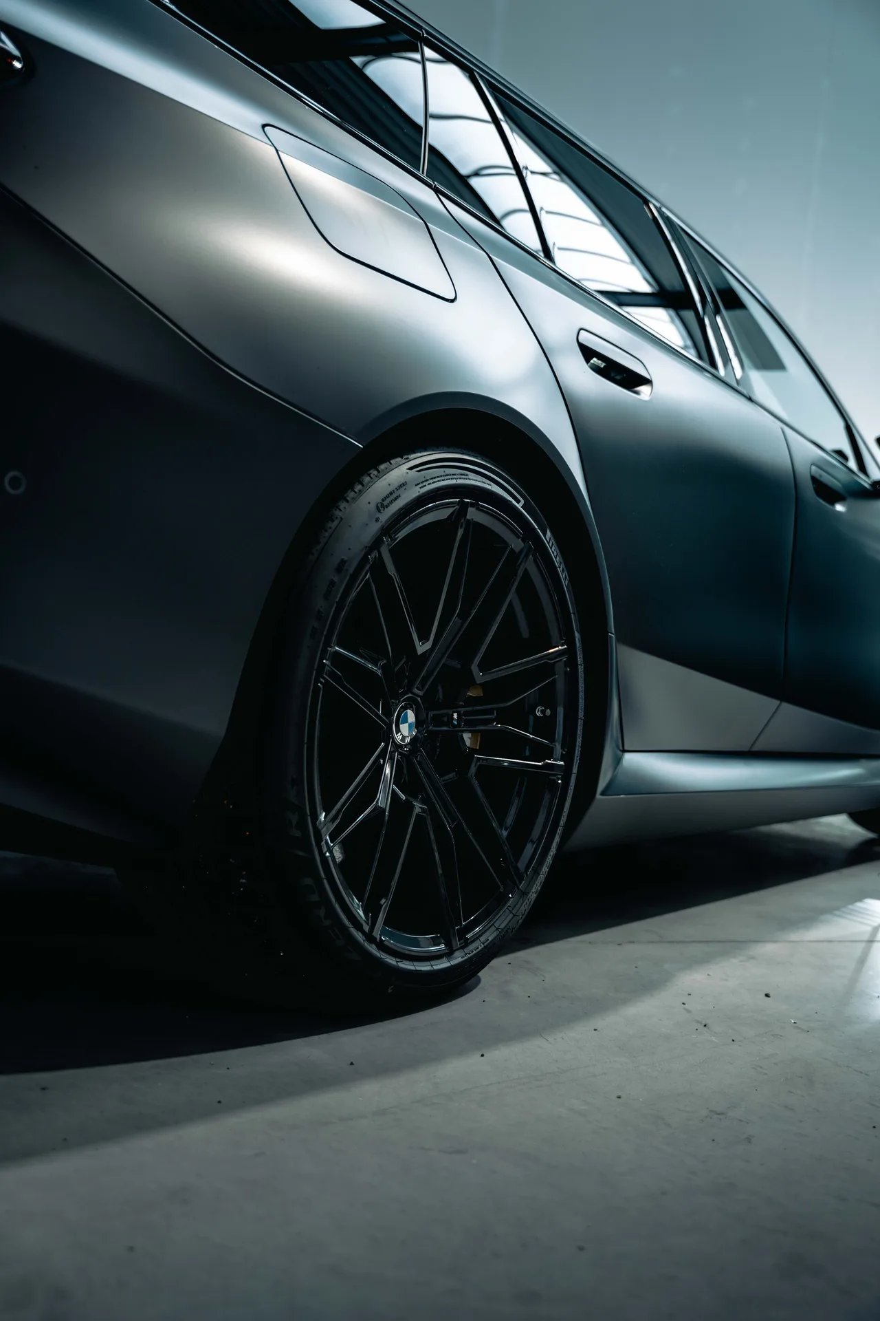 Flank en zwarte velg van een BMW M5 Touring in matgrijze folie
