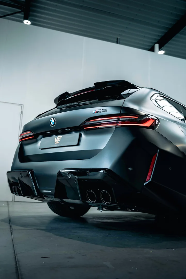 BMW M5 Touring in matgrijs in de witte studio, schuin van achteren