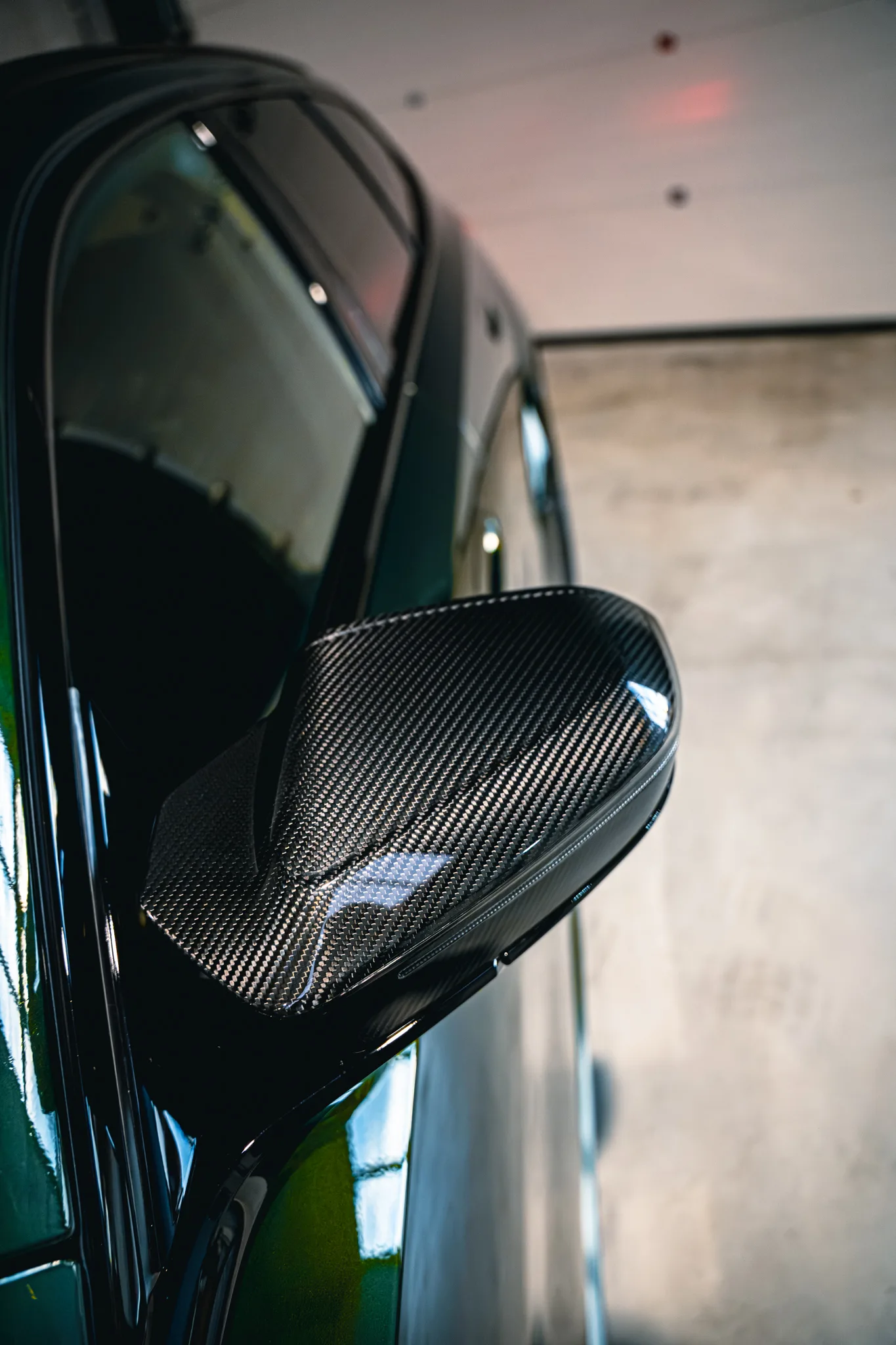 Spiegelkap in carbon fiber op een donkergroene BMW