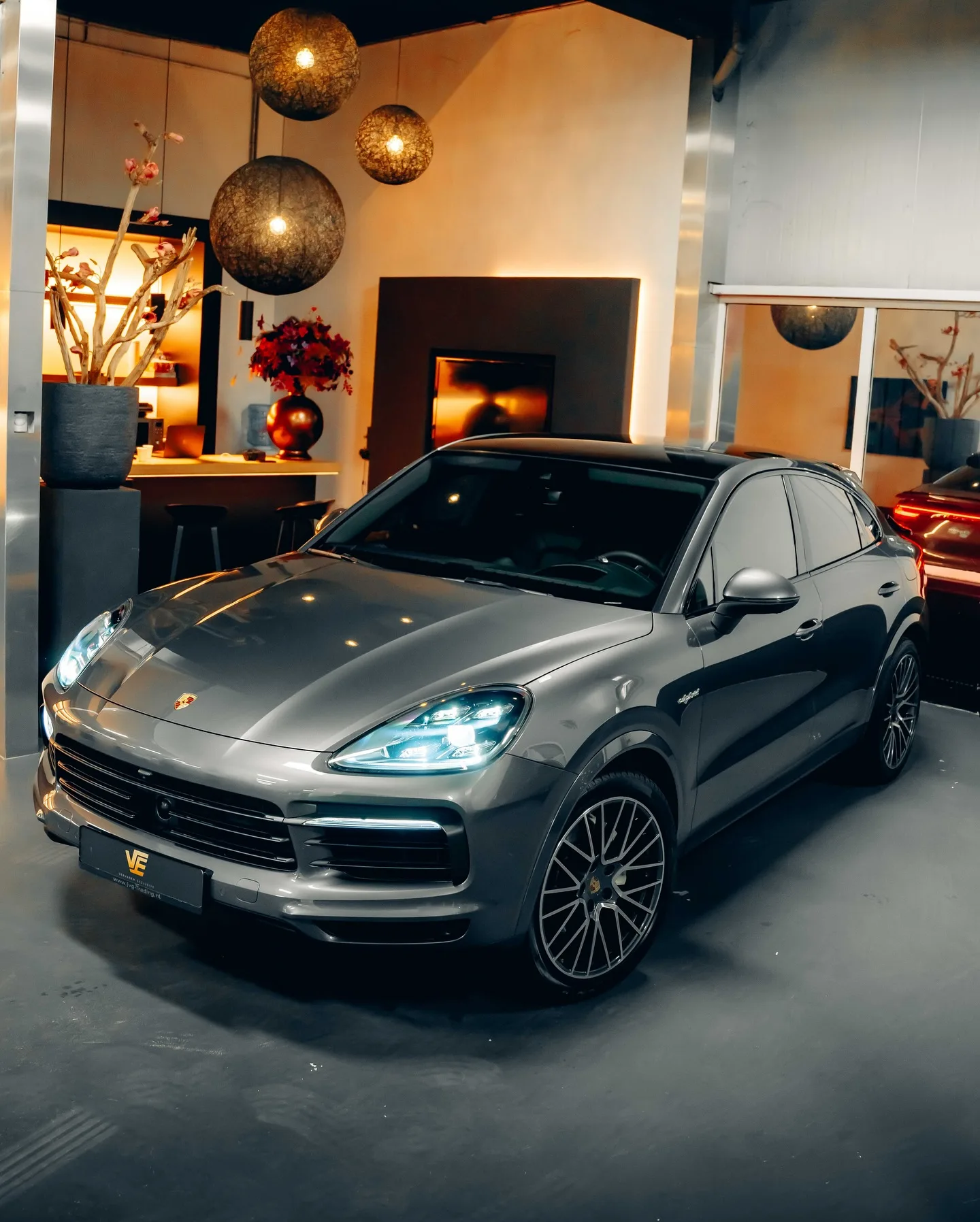 Grijze Porsche Cayenne Coupé in de studio, schuin van voren