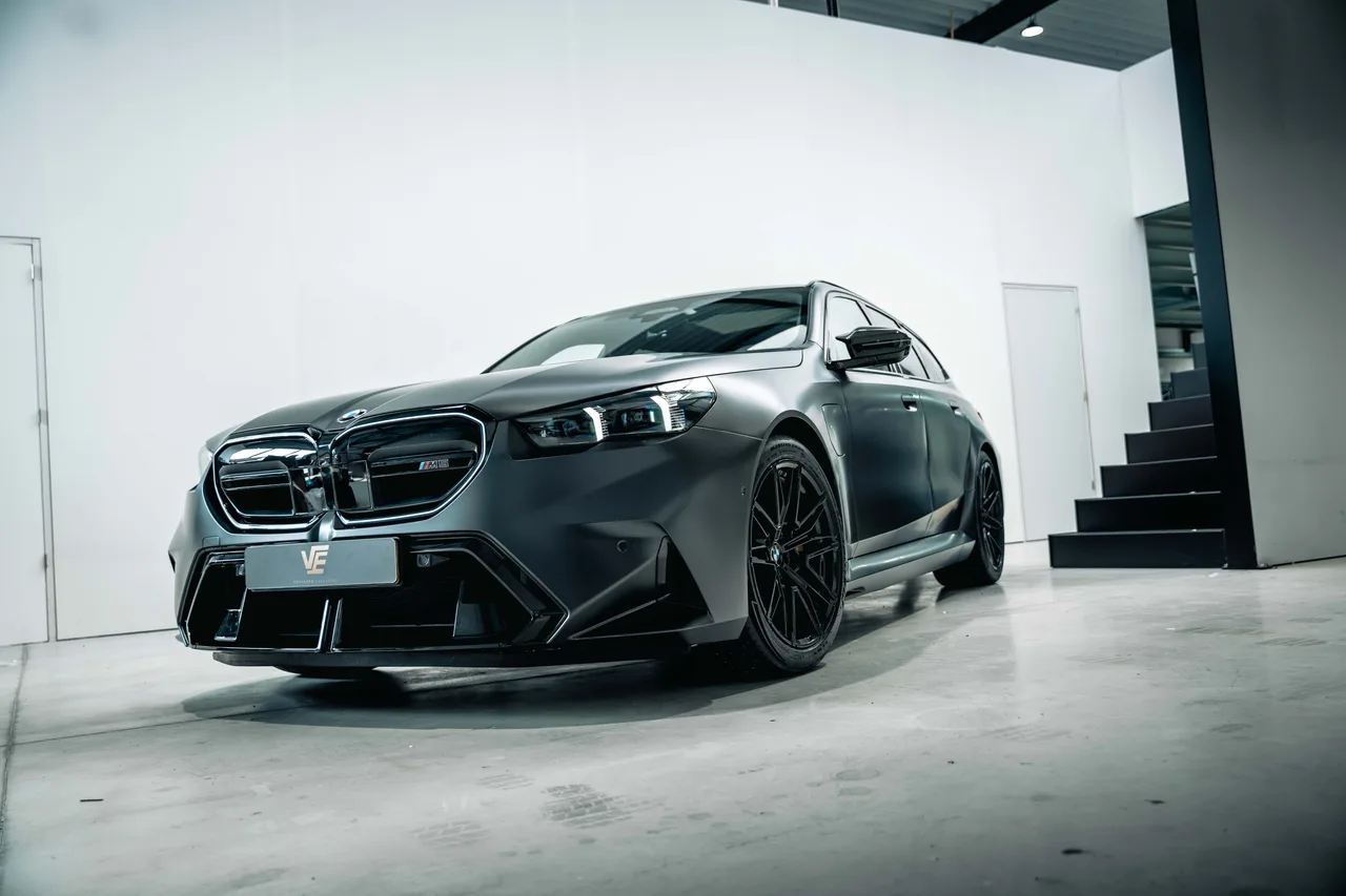 BMW M5 Touring in matgrijs in de witte studio, schuin van voren
