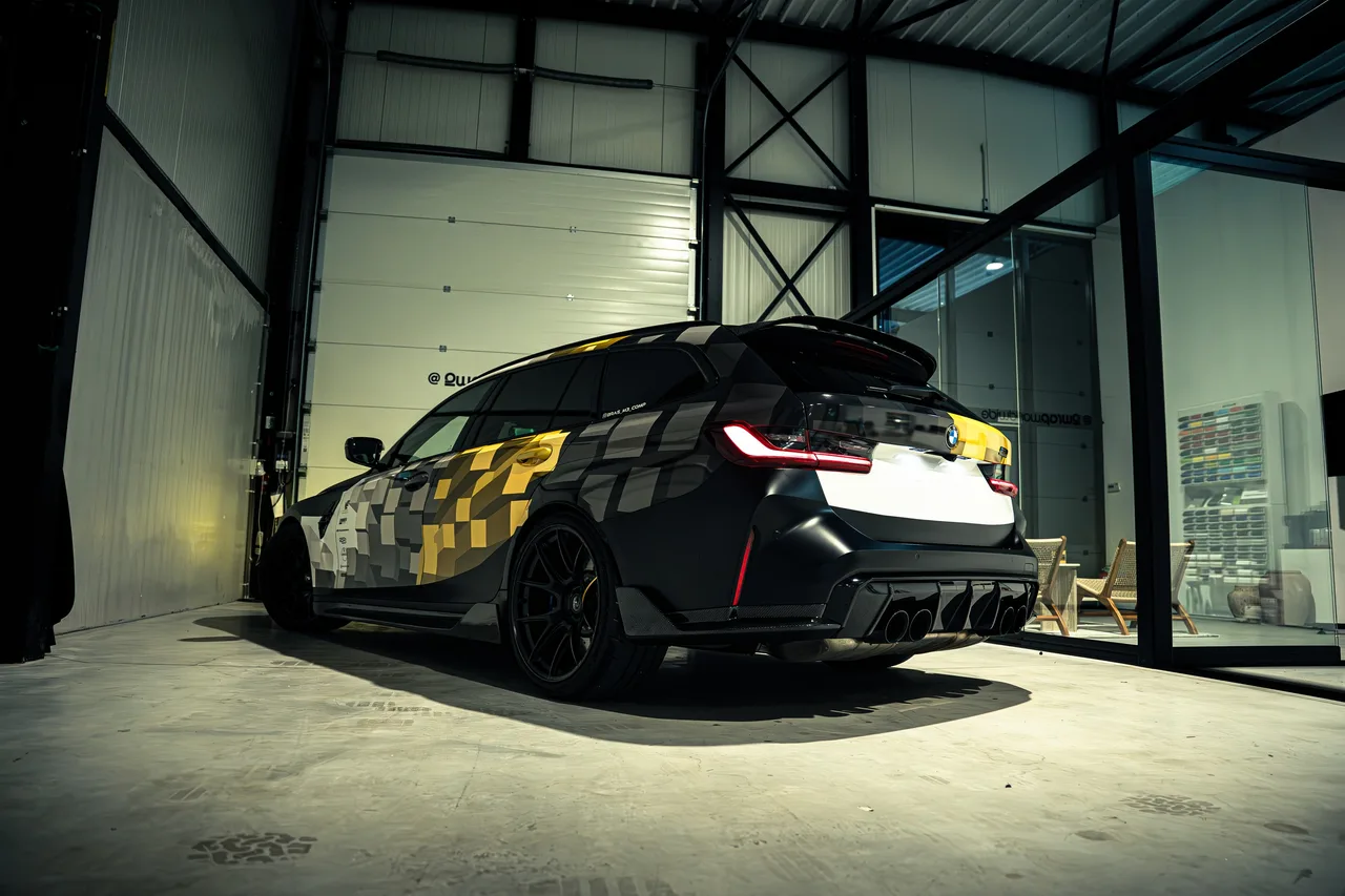 BMW M3 Touring met een custom design wrap in wit, grijs en goud, in de hal