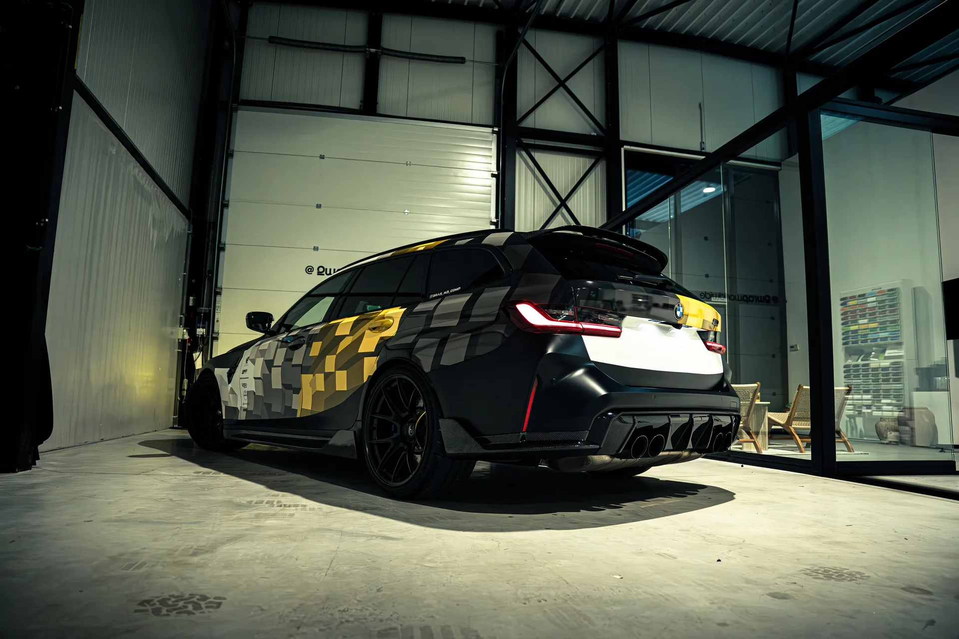 BMW M3 Touring met een custom design wrap in wit, grijs en goud, in de hal