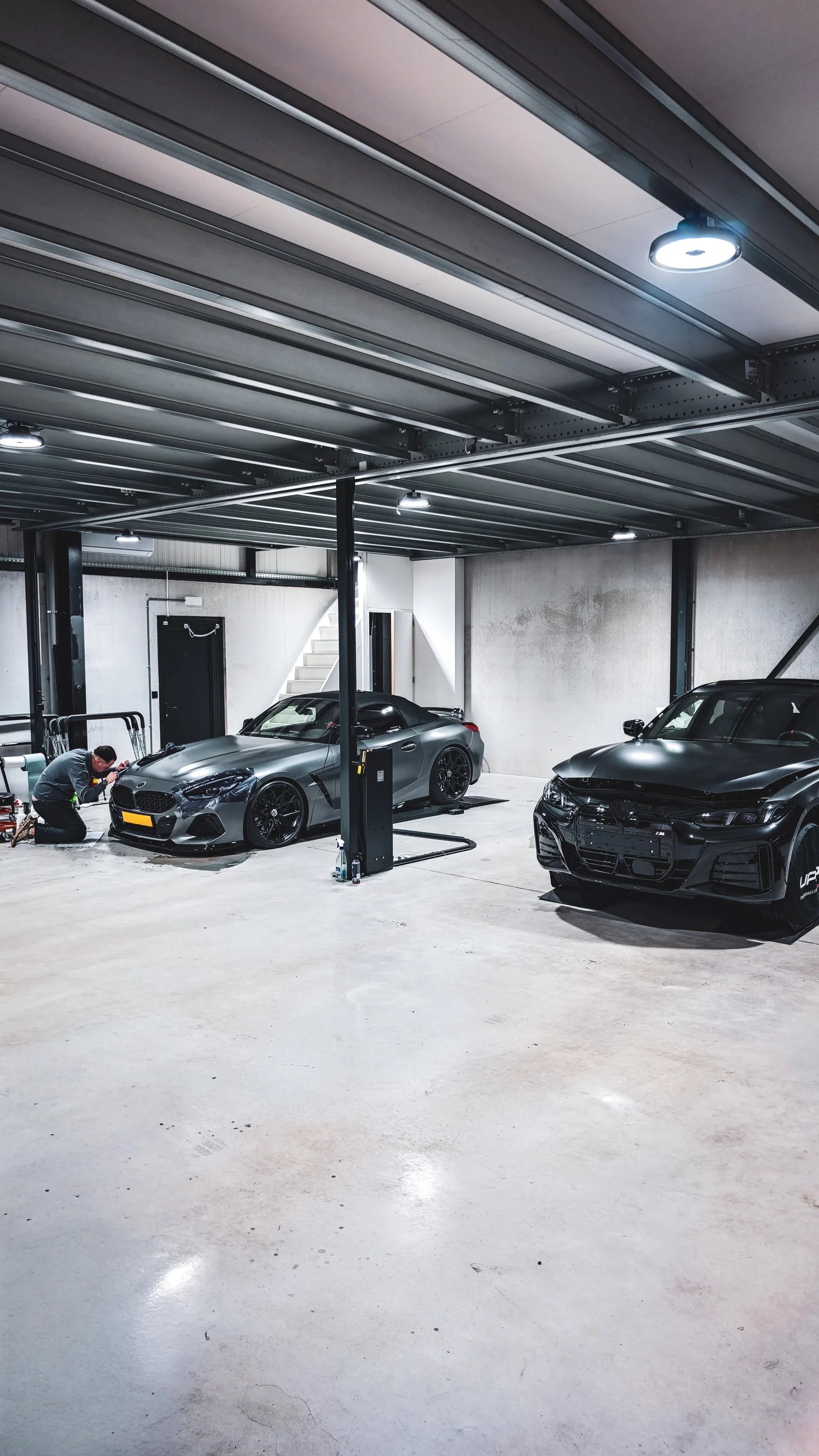 In de hal van Verhagen Exclusive wordt aan de neus van een grijze BMW Z4 gewerkt, met een zwarte BMW ernaast